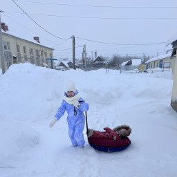 Развлекала сестрёнку: катала её на ватрушке по заснеженному участку