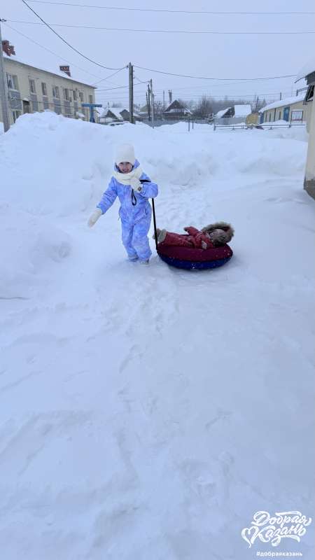 Развлекала сестрёнку: катала её на ватрушке по заснеженному участку